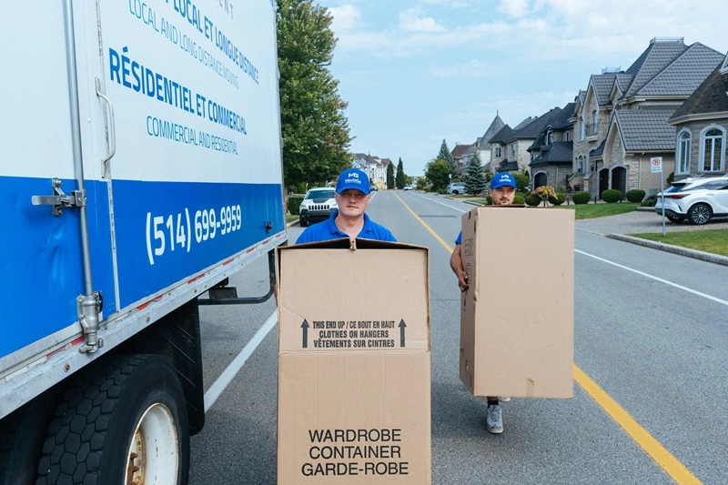 Deux déménageurs MovinGo portent des boîtes garde-robe près du camion