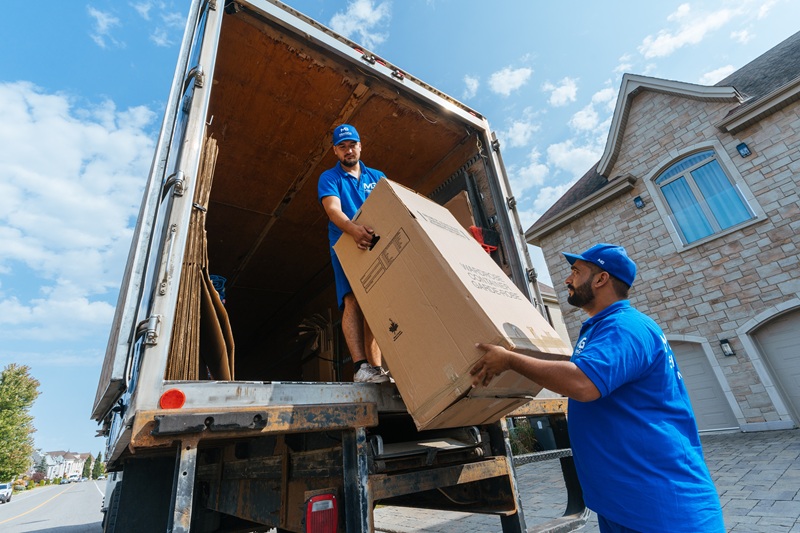 MovinGo movers carefully unloading a large moving box at a home